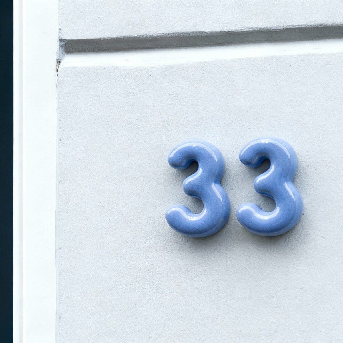 Pair of blue ceramic numbers '33' on a house