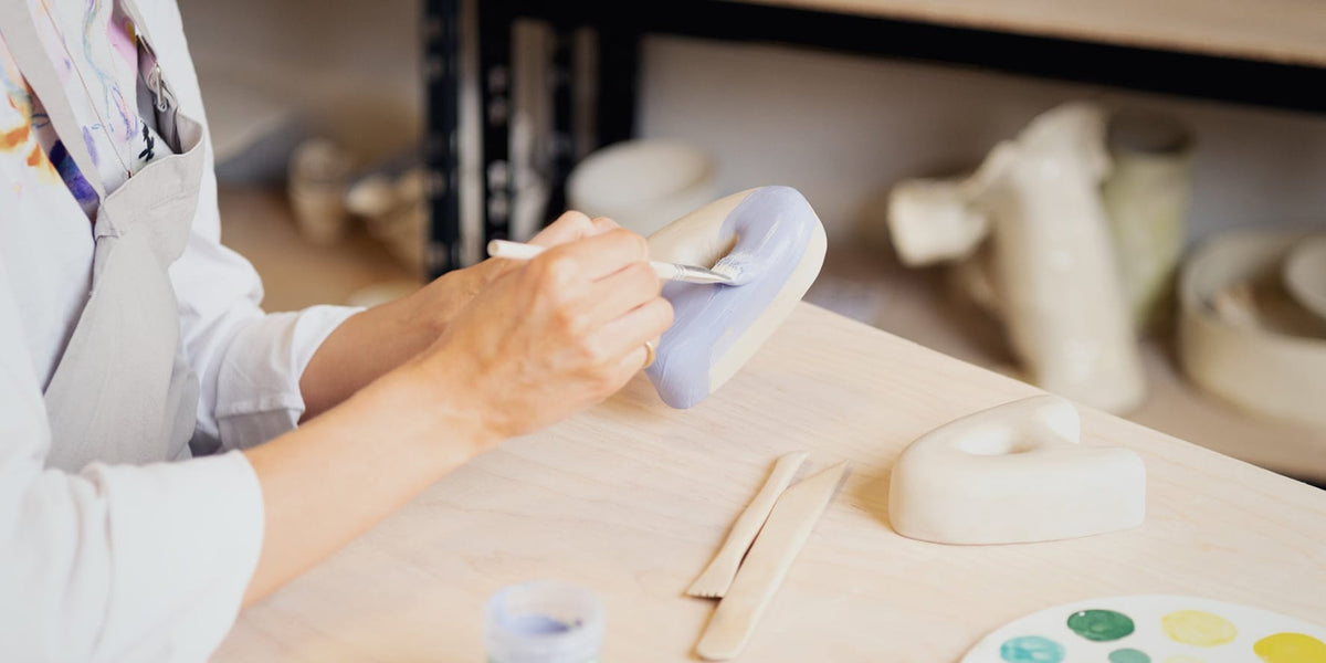 Person working with clay on a letter A in a studio setting